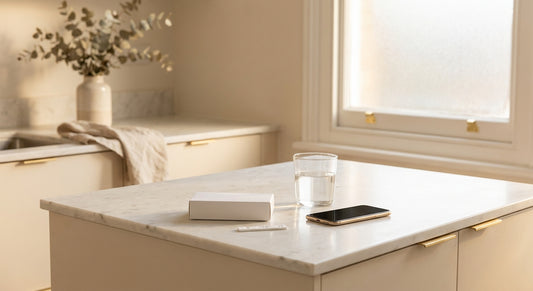 A discreet home medical testing kit resting on a white marble countertop in a softly lit, private modern interior.