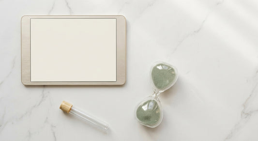 A minimalist flat lay of a digital calendar, hourglass, and specimen tube on a white marble surface, symbolizing timed health testing windows.